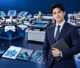 Business professional standing beside textile, precision flatbed, and roll-to-roll screen printing machines and printed samples